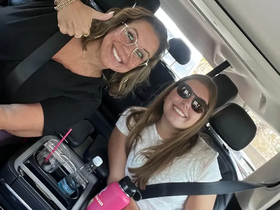 Two smiling passengers with seat belts on in the captain seats of a private Cabo San Lucas airport shuttle