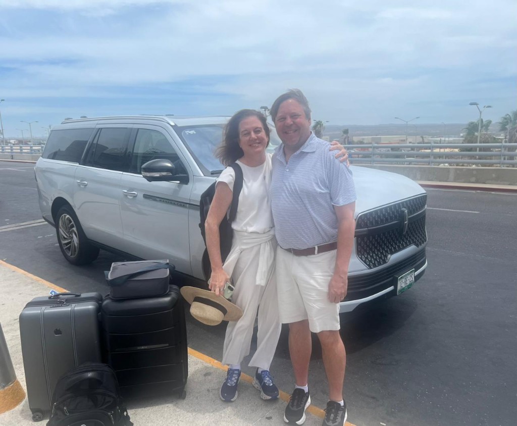 Couple with luggage beside a Lincoln Navigator private Cabo San Lucas airport shuttle